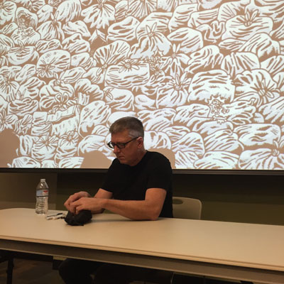 Cartoonist 'Derf' finds a pen to prepare for book signing. Behind him a drawing of garbage bags which appears in his graphic novel, Trashed.